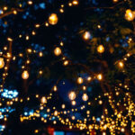 A photograph of a beautifully illuminated outdoor space featuring string lights draped elegantly across trees or a patio
