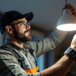 A photograph of a lighting contractor installing a sleek led lamp fixture in a modern residential or commercial space