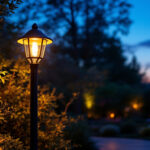 A photograph of a beautifully designed outdoor post light illuminating a cozy outdoor space at dusk