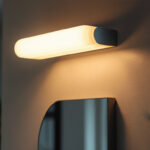 A photograph of a stylish vanity light fixture installed in a modern bathroom setting