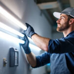 A photograph of a lighting contractor demonstrating the installation of t8 led light bulbs in a commercial setting