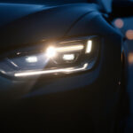 A photograph of a vehicle equipped with high-intensity discharge headlights illuminating a dark road