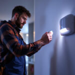 A photograph of a lighting contractor installing an indoor motion sensor in a modern home setting