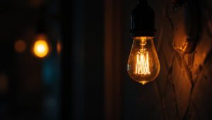 A photograph of a close-up of a flickering light bulb in a dimly lit setting
