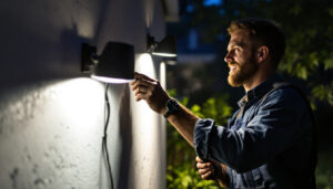 A photograph of a lighting contractor installing high-quality outdoor floodlights in a residential or commercial setting