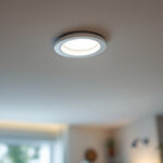 A photograph of a lighting contractor installing energy-efficient led recessed lights in a modern home setting