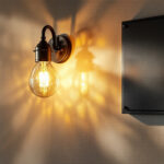 A photograph of a beautifully designed wall sconce light installed next to an elegant plaque on a well-lit wall