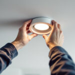A photograph of a skilled lighting contractor installing a recessed bulb in a modern ceiling