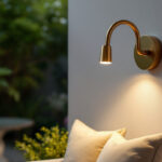 A photograph of a beautifully styled outdoor space featuring a gold gooseneck sconce illuminating a cozy seating area