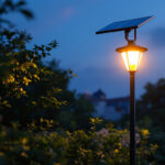 A photograph of a solar lamppost illuminated at dusk