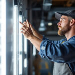 A photograph of a lighting contractor installing 4-foot led bulbs in a commercial space