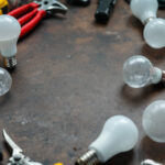 A photograph of a variety of lamp bulb bases displayed alongside lighting tools and equipment