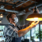 A photograph of a skilled lighting contractor installing or adjusting a stylish commercial light fixture in a modern workspace