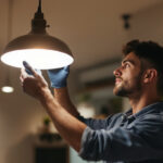 A photograph of a lighting contractor expertly installing or adjusting a norwood three lighting fixture in a well-lit