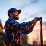 A photograph of a skilled lighting contractor installing a modern led outdoor light fixture in a residential setting during twilight