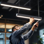 A photograph of capture a photograph of a professional lighting contractor installing the lithonia lighting 4' 237v led fixture in a modern commercial space