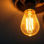 A photograph of a close-up of a flickering light bulb in a ceiling fixture
