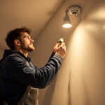 A photograph of a lighting contractor expertly installing a recessed lighting conversion kit in a modern home setting