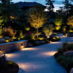A photograph of a beautifully illuminated outdoor space featuring various landscape lighting designs
