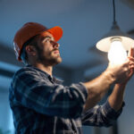 A photograph of a lighting contractor installing led bulbs in a modern light fixture