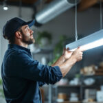 A photograph of a well-lit workspace featuring a lighting contractor installing or showcasing an 8-foot led fixture