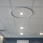 A photograph of a well-lit drop ceiling installation featuring recessed lighting fixtures