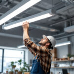 A photograph of a well-lit workspace featuring an 8-foot fluorescent light fixture in action