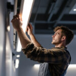 A photograph of a skilled lighting contractor installing or adjusting a sleek striplight in a modern interior space