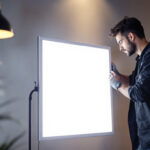 A photograph of a lighting contractor installing or showcasing a 2x4 panel led light in a commercial or residential setting