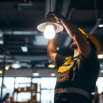 A photograph of a lighting contractor installing a led corn light bulb in a commercial setting