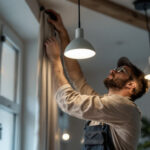 A photograph of a skilled lighting contractor installing or adjusting euri lighting fixtures in a well-lit residential or commercial space