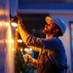 A photograph of a skilled lighting contractor installing or adjusting modern led lights and fixtures in a residential or commercial setting
