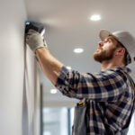 A photograph of a lighting contractor expertly installing led recess lights in a modern residential setting