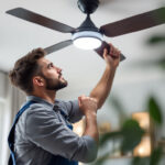 A photograph of a skilled lighting contractor installing an elegant ceiling fan with integrated lighting in a stylish home setting