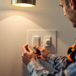 A photograph of a skilled lighting contractor installing paddle switches in a modern home setting