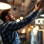 A photograph of a skilled lighting contractor meticulously adjusting and installing various types of metal light fixtures in a modern interior space