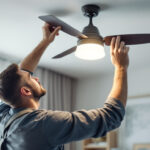 A photograph of a skilled lighting contractor installing a stylish ceiling fan light fixture in a modern living space