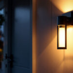 A photograph of a modern front door with an aesthetically pleasing lamp illuminated at dusk