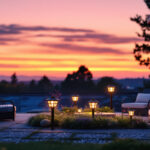 A photograph of a beautifully illuminated outdoor space featuring various styles of solar lighting