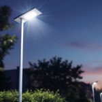A photograph of a solar-powered light pole installed in a well-lit outdoor setting