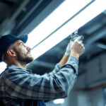 A photograph of a lighting contractor installing a 2x4 led light fixture in a commercial space