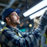 A photograph of a lighting contractor installing or examining four-foot led lights in a commercial or residential setting