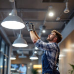 A photograph of a lighting contractor installing recessed led light fixtures in a modern commercial space