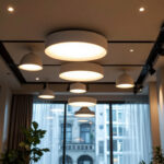 A photograph of a well-lit room showcasing various sizes of recessed lighting fixtures installed in a stylish ceiling