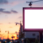 A photograph of a brightly illuminated outdoor led sign in a commercial setting at dusk