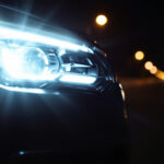 A photograph of a modern sylvania automotive headlight illuminating a dark road at night