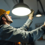 A photograph of a skilled lighting contractor expertly installing a stylish luminaire lighting fixture in a modern interior space