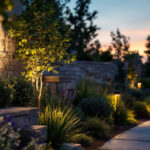 A photograph of a professional lighting contractor installing waterproof outdoor led flood lights in a landscaped area at dusk