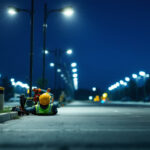 A photograph of a lighting contractor installing or adjusting parking lamps in a well-lit parking lot