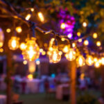 A photograph of a lighting contractor skillfully installing construction string lights at a vibrant outdoor event